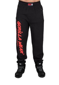 Sorte sweatpants med et struktureret stof, der har et fremtrædende rødt "GORILLA WEAR" logo på venstre ben og elastiske manchetter ved anklerne.
