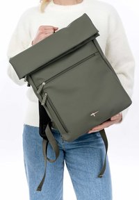 Sac à dos à rabat vert olive fabriqué en matériau durable, doté d'une poche zippée à l'avant, de bretelles réglables et d'un détail de logo subtil.
