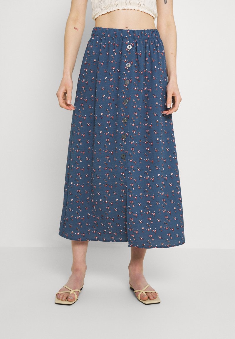 Falda midi azul con un cinturón elástico, que presenta un cierre de botones en la parte delantera y pequeños patrones de flores blancas y rosas. Textura suave.