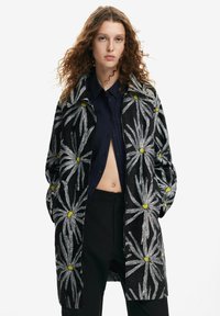 Black jacket featuring silver floral embroidery with yellow accents, long sleeves, a relaxed fit, and a zip-front closure.