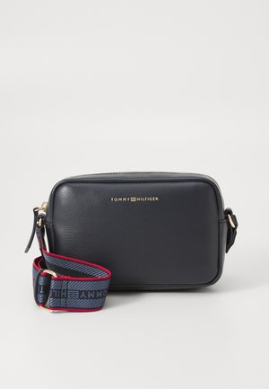 Navy leather handbag with gold logo, rectangular shape, zip closure, and a patterned fabric strap in navy with red accents.