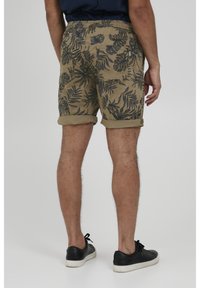 Shorts kaki cu un model de frunze tropicale verzi închise, realizate dintr-un material ușor, cu manșete răsucite și o croială lejeră.
