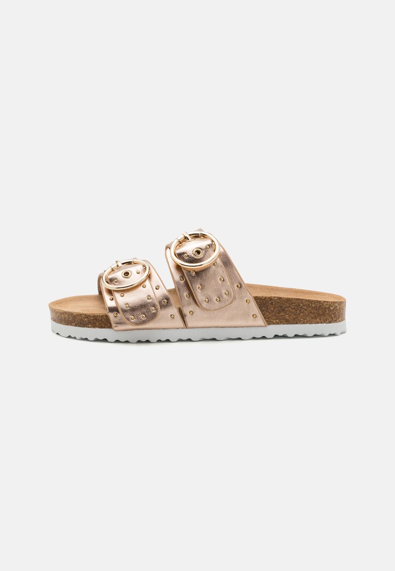 Ljusrosa metalliska sandaler med två breda remmar som har runda spännen och nitar. Korkfotbädd och vit gummisula med texturerad sula.