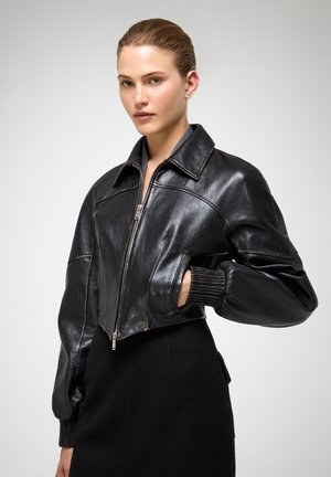Zwarte cropped leren jas met een ritssluiting aan de voorkant, grote kraag en geribde manchetten. Gladde textuur met zichtbare stikseldetails.