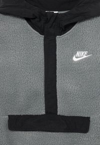 Casaco de fleece cinza da Nike com fecho éclair preto e acabamento da capuz, apresentando o logotipo branco da Nike no peito.
