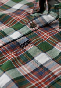 Geruit overhemd met groene, witte en rode kleuren. Gemaakt van zachte stof met knoopdetails en een zichtbaar logolabel aan de voorkant.