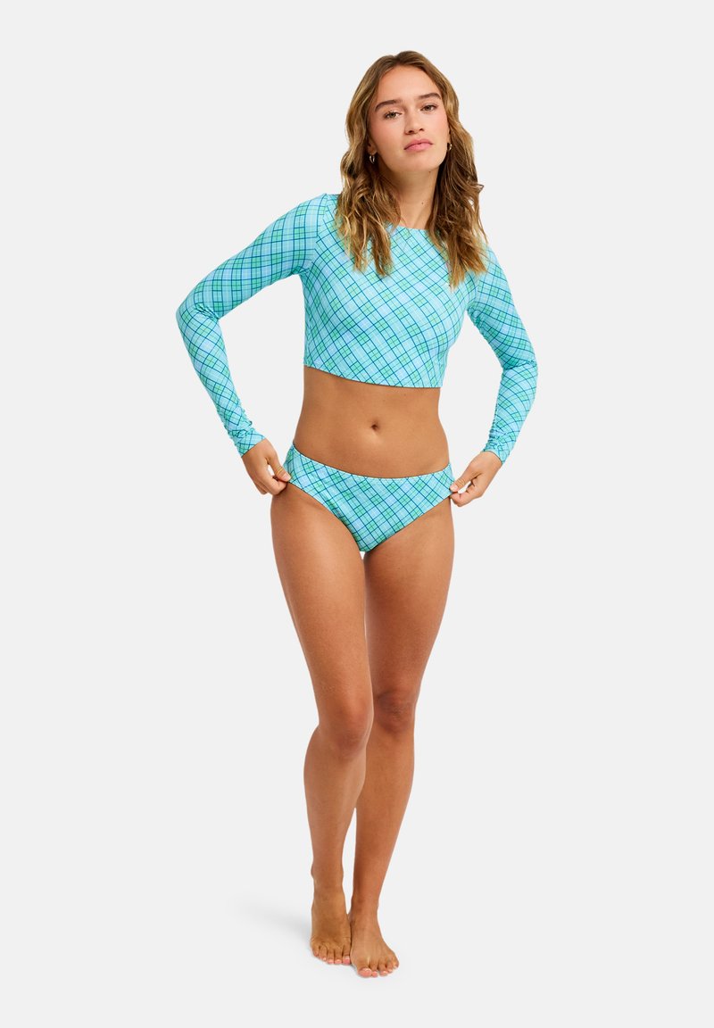 Σετ μακρυμάνικου τοπ cropped και μπικίνι σε ανοιχτό γαλάζιο με σχέδιο πλέγματος. Το υλικό είναι λείο και το σχέδιο εφαρμοστό.