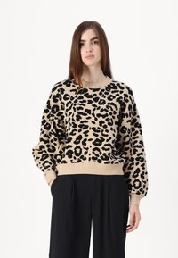 Bež pulover s crnim leopard uzorkom, s okruglim izrezom, opuštenim krojem i rebrastim manžetama i donjim rubom. Mekana pletenina.