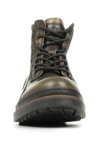 Bottine en cuir marron avec lacets noirs, fermeture éclair sur le côté, surface texturée, bout rond, semelle en caoutchouc et bord en violet contrastant le long du bord de la semelle.