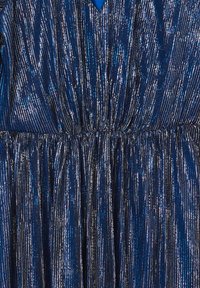 Robe bleu marine avec plissés métalliques, présentant une taille froncée et un décolleté en V. Le tissu a une texture soyeuse avec des accents scintillants.