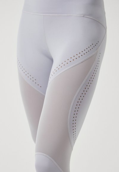Lichtgrijze legging met netpanelen en perforaties aan de zijkanten, gemaakt van een rekbare, vochtregulerende stof.