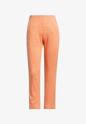Leggings orange avec un petit motif de cœurs blancs. Fabriqués en tissu extensible, avec une texture lisse et une coupe ajustée.