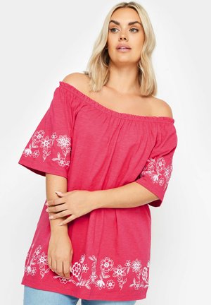 Top rosa senza spalline con maniche corte, caratterizzato da ricami floreali bianchi lungo le maniche e l'orlo. Materiale morbido e leggero.