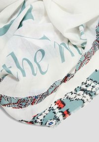 Lichte witte sjaal met aqua kleurige letters en een patroonrand in tinten van rood, zwart en blauw. Getextuurde afwerking met franjes aan de randen.