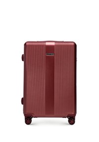 Red hard-shell suitcase with vertical grooves, dual wheels, and a black brand emblem. Features a sturdy handle for easy transport.