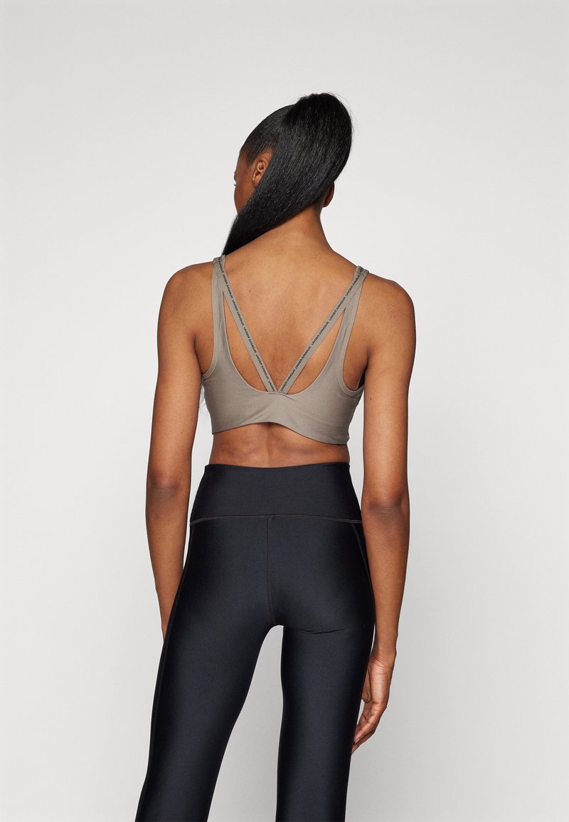 Sostenedor deportivo gris con tirantes cruzados en la espalda, combinado con leggings negros de cintura alta. Tela suave y elástica en todo.