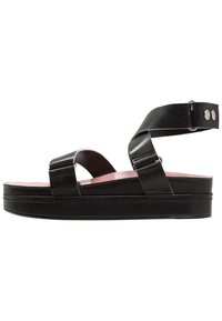 Černé kožené platformové sandály s širokými popruhy, růžovou stélkou a kovovými akcenty. Mají plochou, pevnou podrážku se švovým detailem.