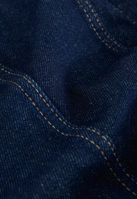 Mørkeblå denimstof med nærbillede, der viser den detaljerede tekstur og orange dobbeltstinglinjer.