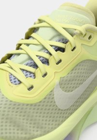 Ανοιχτό κίτρινο παπούτσι τρεξίματος Nike Zoom Fly με επάνω μέρος από δίχτυ, επίπεδα κορδόνια και εμφανές λογότυπο Swoosh σε εκρού χρώμα. Διακρίνεται η υφασμένη σόλα.