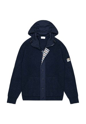 Giacca blu navy con trama lavorata a maglia, cappuccio staccabile e fodera a quadri. Include tasche frontali e chiusure con bottoni a pressione.