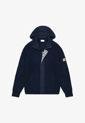 Giacca blu navy con trama lavorata a maglia, cappuccio staccabile e fodera a quadri. Include tasche frontali e chiusure con bottoni a pressione.