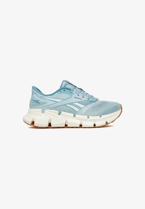 Světle modrá běžecká bota Reebok s prodyšným nodovým svrškem, bílou členitou tlustou podrážkou a gumově zbarveným spodkem, zobrazena z profilu směrem doprava.