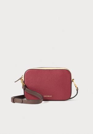 Burgunderrød lærcrossbody-veske med en pebblelignende tekstur, gullfargede detaljer og et avtakbart, mørkebrunt stroppe. Rektangulær form med glidelås på toppen.