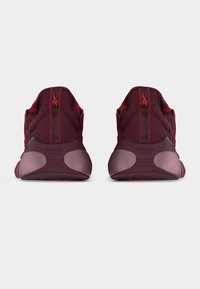 Ζευγάρι σκούρα κόκκινων αθλητικών παπουτσιών με παχιά σόλα, με το κείμενο «NANO GYM» στη φτέρνα, σε θέα από πίσω πάνω σε απλό φόντο.