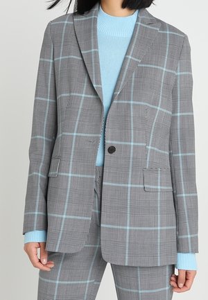 Grå rutig blazer med ljusblå linjer, enkel knäppning, två framfickor, textil med struktur, ihopparad med en ljusblå tröja.