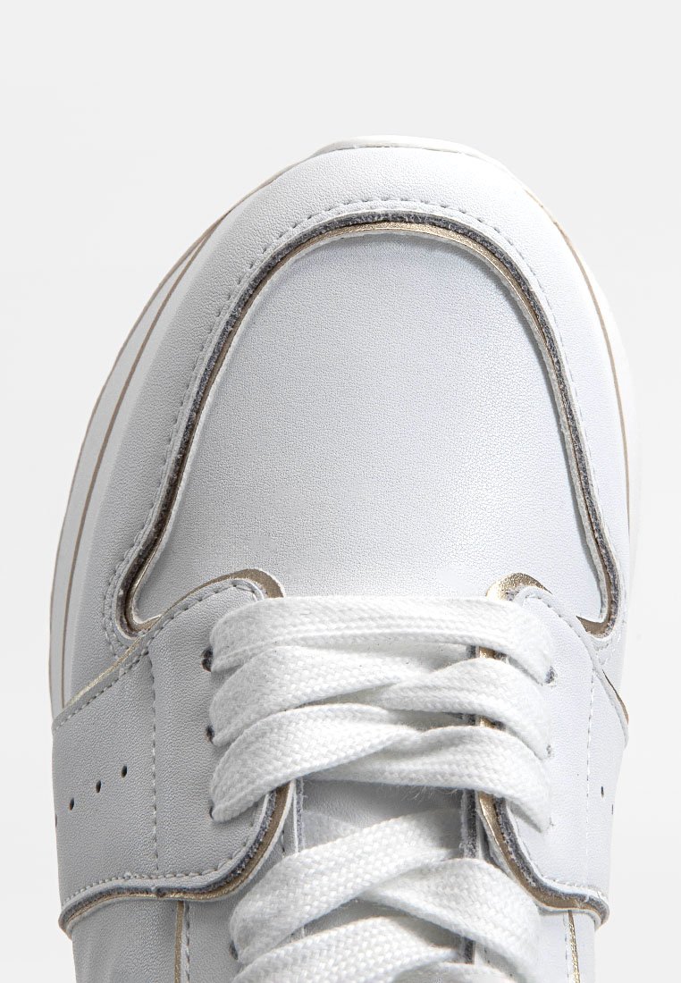 Zapatilla blanca con un empeine sintético suave, puntera redondeada, sistema de cordones prominente y sutiles acentos dorados a lo largo de la costura.