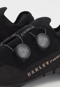 Juodi sportiniai bateliai su tekstūruotu trikotažo viršumi, dvigubu BOA raištelių sistema ir spalvingu "DAKLEY PWR" logotipu šone.