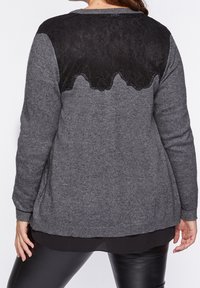 Šedý svetr s černou krajkou na živůtku. Dlouhé rukávy a zaoblený okraj. Měkká pletenina s texturovaným vzorem na horní části zad.