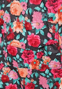 Tkanina w kwiatowy wzór w odcieniach czerwieni, różu i pomarańczy na czarnym tle; posiada kieszeń naszywaną i widoczne detale szwów.