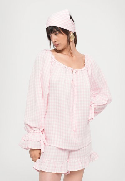 Ensemble de pyjama à carreaux roses comprenant un haut avec encolure froncée et nœud en ruban, et un short avec un ourlet volanté et des poignets élastiques.