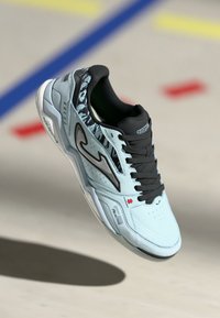 Világoskék sportcipő fekete kiegészítőkkel, texturált mintázattal a sarkán, perforált orrrésszel és fekete fűzőkkel. Gumi talp logó részletekkel.
