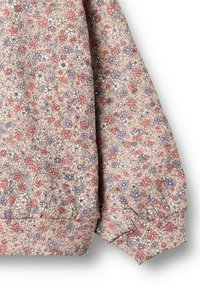 Blumenmusterstoff, überwiegend hellrosa, mit kleinen lila und roten Blumen. Hat elastische Bündchen und eine weiche, strukturierte Oberfläche.