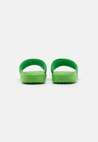 Des sandales vertes en matériau plastique lisse, avec un dos ouvert et une semelle intérieure texturée. La semelle présente un motif segmenté pour une meilleure traction.