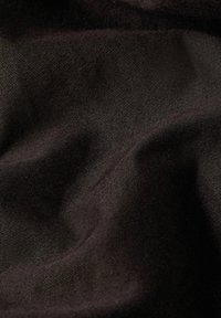 Tessuto nero con una consistenza liscia e una leggera lucentezza, caratterizzato da righe diagonali e pieghe delicate, creando profondità e dimensione.