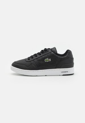 Baskets basses Lacoste noires avec semelle blanche, lacets et logo crocodile vert sur le côté, vues de l'extérieur.
