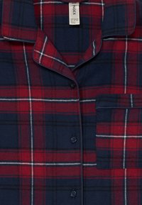 Rot und marineblau kariertes Hemd mit Knopfleiste, mit Notch-Kragen, einer einzelnen Brusttasche und weißen Nähdetails. Aus weichem Stoff gefertigt.