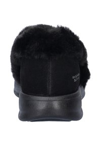 Zwarte instapschoenen met een zachte nepbonten kraag, bovenwerk van suede, een gestructureerde rubberen zool en minimale branding aan de zijkant.