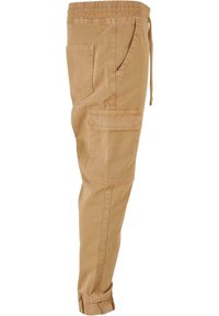 Pantalon cargo marron clair effilé avec taille élastique, cordon de serrage, poches latérales et chevilles resserrées, présenté sur fond blanc.