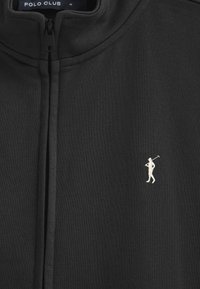 Giubbotto nero con zip, colletto alto, texture del tessuto morbida, con un piccolo logo di un golfista bianco sul lato sinistro.