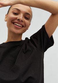 Zwart, kortemouw t-shirt van katoen, met een losse pasvorm en zachte textuur, ronde halslijn en minimale naden.