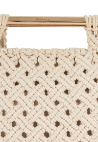 Knit handbag in cream cotton with a diagonal weave pattern, featuring gold hardware at the top and distinctive cut-out detailing.