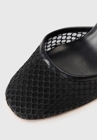 Infradito in rete nera con un motivo esagonale sul materiale superiore, completati da una finitura in pelle nera liscia lungo il bordo.
