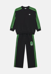 Schwarzes Sweat-Set mit grünen Streifen auf den Schultern und an den Seiten, begleitet von einem grafischen Logo auf der Hose. Weiches Material, lockere Passform.