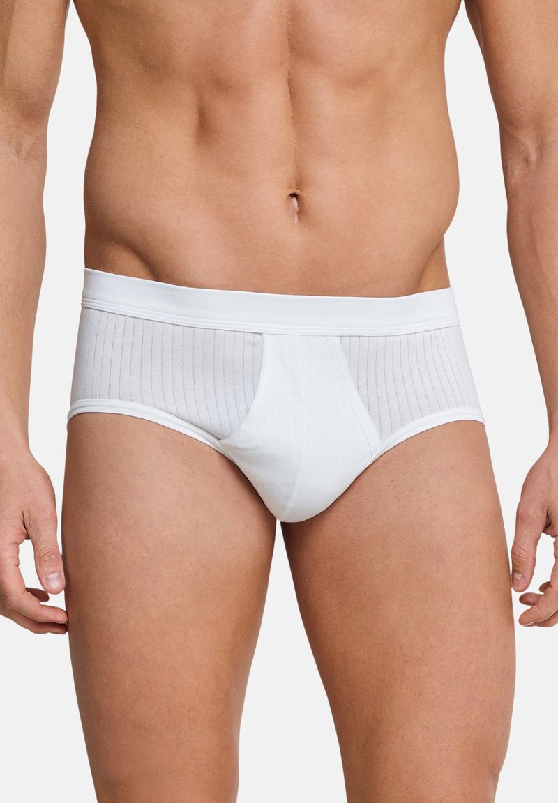 Slip di cotone bianco con un pannello trasparente a strisce verticali, una tasca di supporto e una morbida vita. Texture liscia, design aderente.