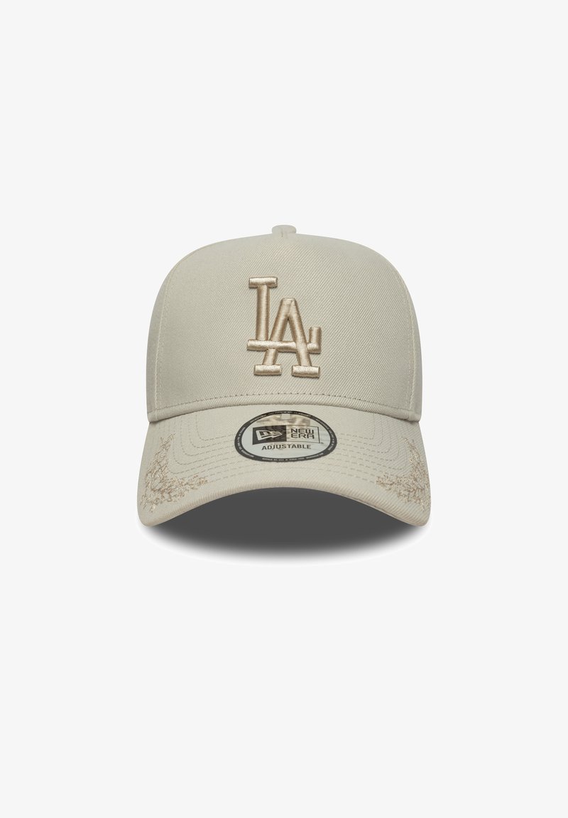 Beige cap with a structured design, featuring a raised beige "LA" logo, textured fabric, and a curved visor. Adjustable strap visible.