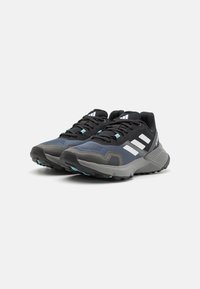 Black and navy athletic shoes with a textured mesh upper, three white stripes on the side, and a rugged gray outsole.